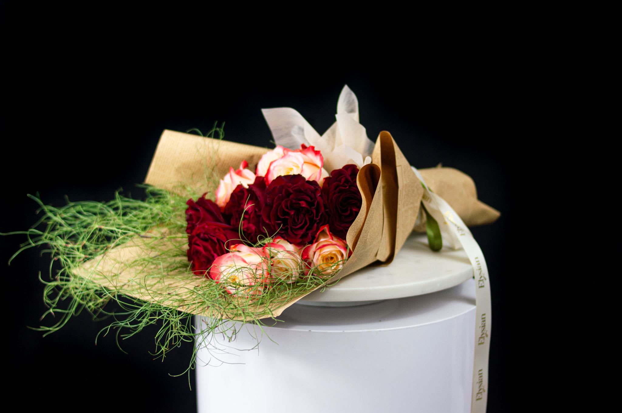 Crimson Muse - Bold, dramatic, and irresistibly romantic. Crimson Muse is a striking bouquet featuring velvety deep red roses paired with soft blush accents, framed by airy, sculptural greenery. The contrast between intensity and softness creates a powerful expression of passion, desire, and elegance.  Wrapped in natural paper with flowing textures, this bouquet is designed to feel artistic and intentional—perfect for grand gestures, anniversaries, or when love deserves to be felt at full volume.  A muse for the heart, inspired by love that leaves a mark. ️  Disclaimer: Due to the seasonal nature of flowers, we select the freshest blooms available. Flower varieties may vary, but we always preserve the color palette, style, and overall aesthetic shown.