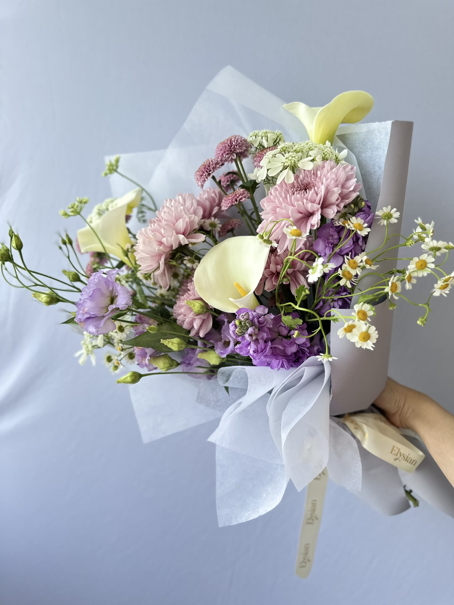 Purple Dream - Indulge in the perfect balance of nature with Purple Dream. This stunning bouquet features a delicate combination of purple, violet, white, and hints of yellow flowers including calla lily, chrysanthemum, lisianthus, and stocks. Elevate any occasion with the beauty of nature.  Disclaimer  Flower varieties and exact shades may vary based on seasonal availability. Substitutions may be made while maintaining the overall color palette, style, and value of the arrangement to ensure the freshest blooms and the highest design quality.