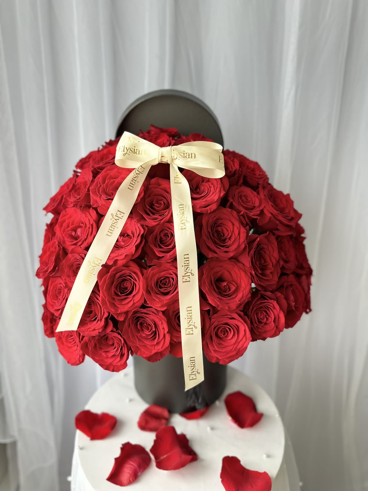 Grand Symphony of Roses - Introducing Grand Symphony of Roses, an opulent flower box arrangement designed to impress from every angle. This stunning display features 50 fresh, premium red roses, each handpicked for its lush petals and vibrant color, symbolizing profound love and admiration.  These exquisite roses are meticulously arranged in a sophisticated flower box at a perfect 180-degree angle, ensuring a breathtaking view from any perspective.  Whether for a grand celebration, a romantic gesture or to express your deepest emotions, the Grand Symphony of Roses is an extraordinary choice.