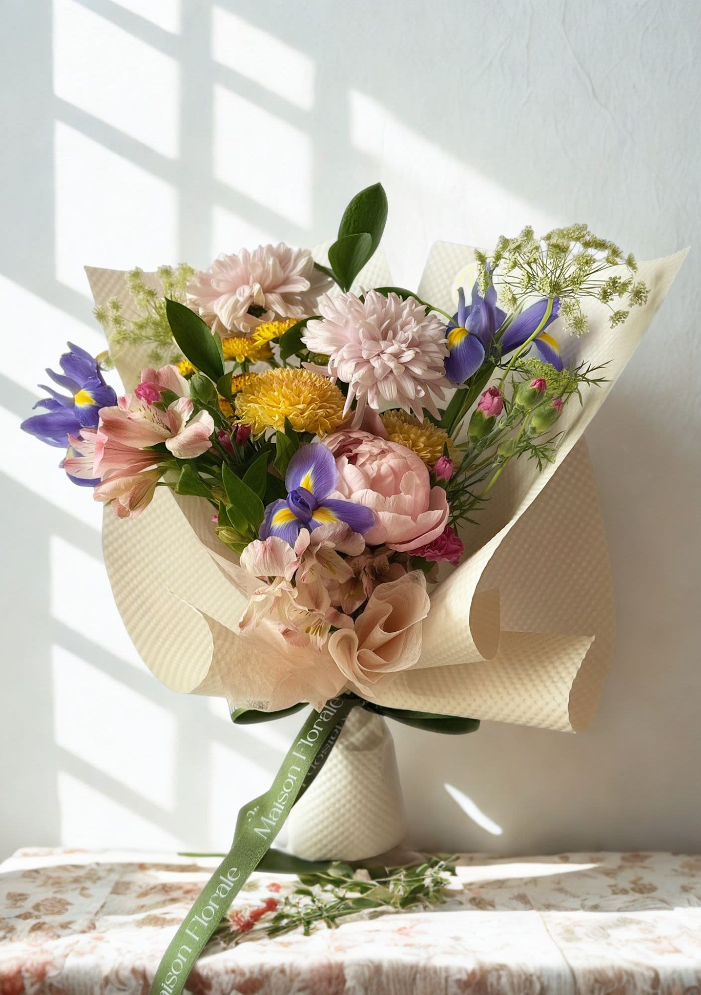 Á La Maison  - À La Maison is a bouquet born entirely from the designer's eye, shaped by the season, and guided by instinct rather than a brief. No two are ever alike.  Each week, we handpick the finest seasonal stems that arrive at our studio — the peonies blushing at their peak, the iris just beginning to unfurl, the chrysanthemums catching the light in unexpected ways — and arrange them in the way that feels most alive, most considered, most us.  This is not a bouquet you design. It is one you trust us to design for you. 
