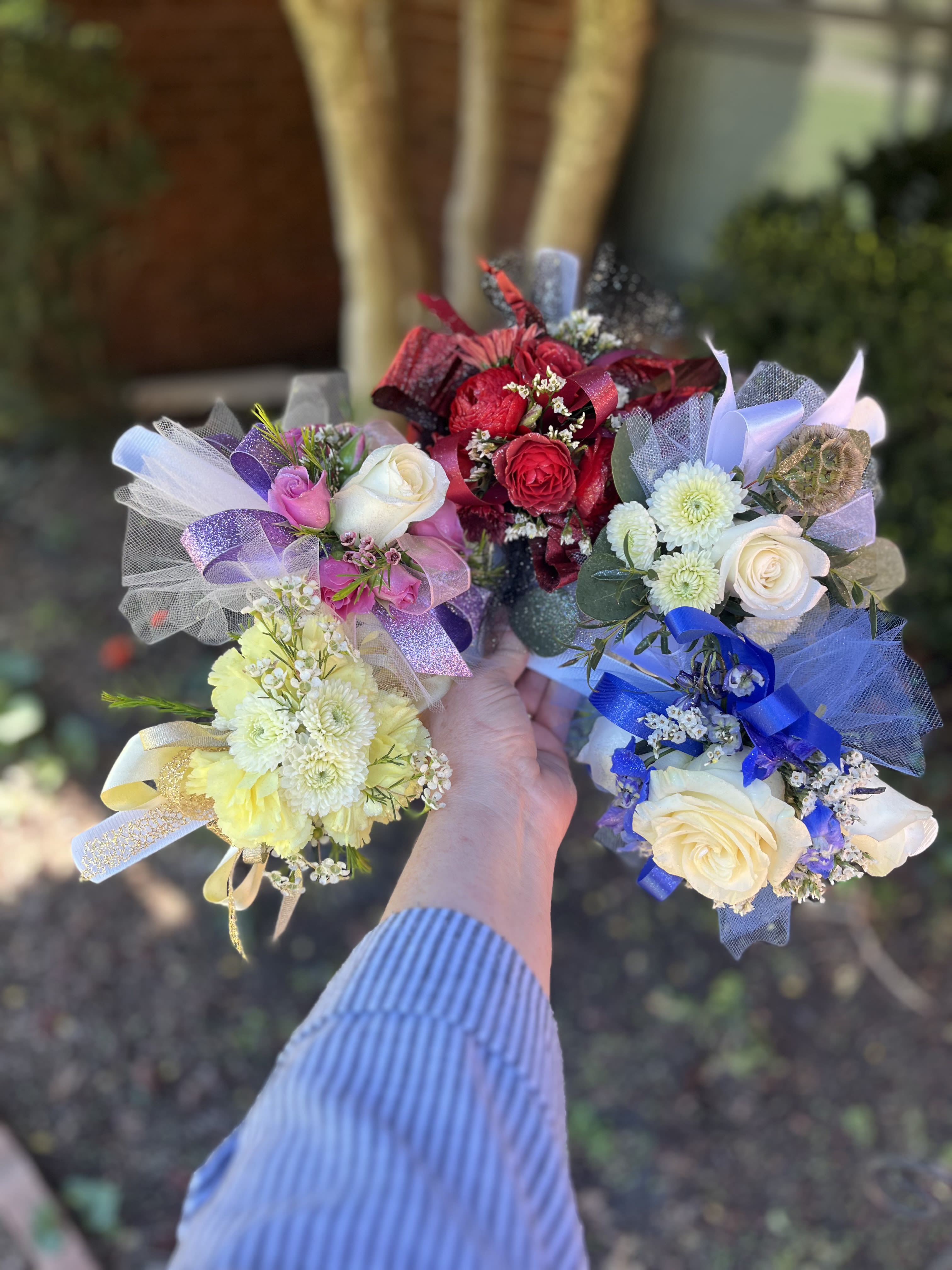 Standard Corsage - Soft, hand-tied corsages that feel like a pocket-sized celebration - perfect as a birthday bouquet, thank-you gift, or springtime pick-me-up. These Standard Corsage arrangements present mixed-color and single-tone options (white, pink, red) so you can choose a palette that matches the moment; each one is crafted for someone you want to make feel seen and cherished.  Each corsage clusters roses, chrysanthemums and complementary blooms into a small handheld spray, wrapped in sheer tulle and finished with decorative satin ribbon for a delicate, wearable look. Colorways include romantic reds, sweet pinks, pure whites and cheerful mixed palettes with yellow and pale blue accents; textures range from the rose's velvety petals to the chrysanthemum's airy fullness. The compact size makes them easy to hold, tuck into a gift, or pin on a lapel.  Ideal for presenting to a friend, teacher, mom, or special guest, these corsages convey warmth and celebration without fuss. Order by color to match an outfit or occasion; treat them gently, keep away from direct heat, and refresh with a light mist of water if needed to keep blooms looking their best.