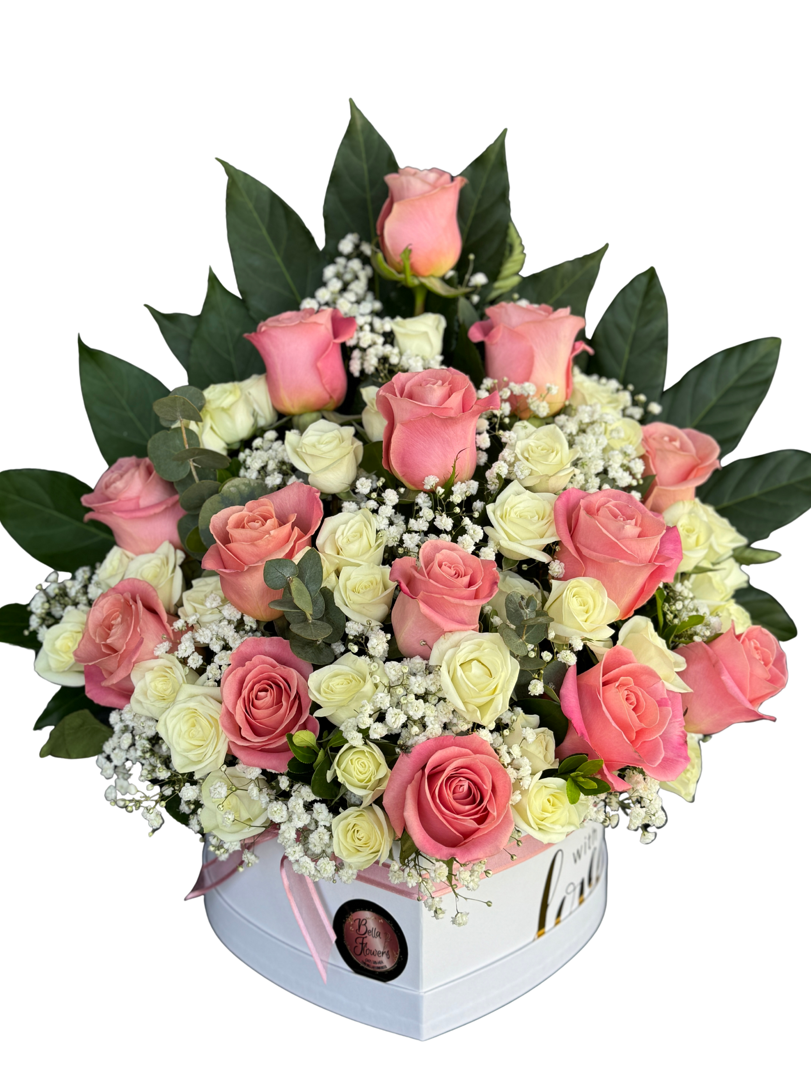 Rose Arrangement - A lush cluster of pink and ivory roses arranged inside a white heart-shaped box makes this flower arrangement an unmistakable romantic gift - perfect as an anniversary bouquet, a Valentine's Day surprise, or a heartfelt thank-you. The compact, gift-box presentation and soft pink-and-white palette say "I care" in a polished, celebratory way that will make the person you're thinking of feel truly cherished.  The arrangement features tightly layered pink and white roses mingled with petite filler blooms and dark green foliage that rises behind the roses for contrast and height. A delicate pink ribbon finishes the heart-shaped box, creating an elegant keepsake presentation. The dense, cushion-like styling highlights the roses' velvety petals and keeps the composition feeling fresh and full.  Designed to arrive ready to display, this boxed rose arrangement is ideal for sending directly to a loved one or bringing to a special occasion. To keep the flowers looking their best, place the box in a cool spot away from direct sunlight and replace water or floral foam as needed; sizing and exact stem count may vary by availability.