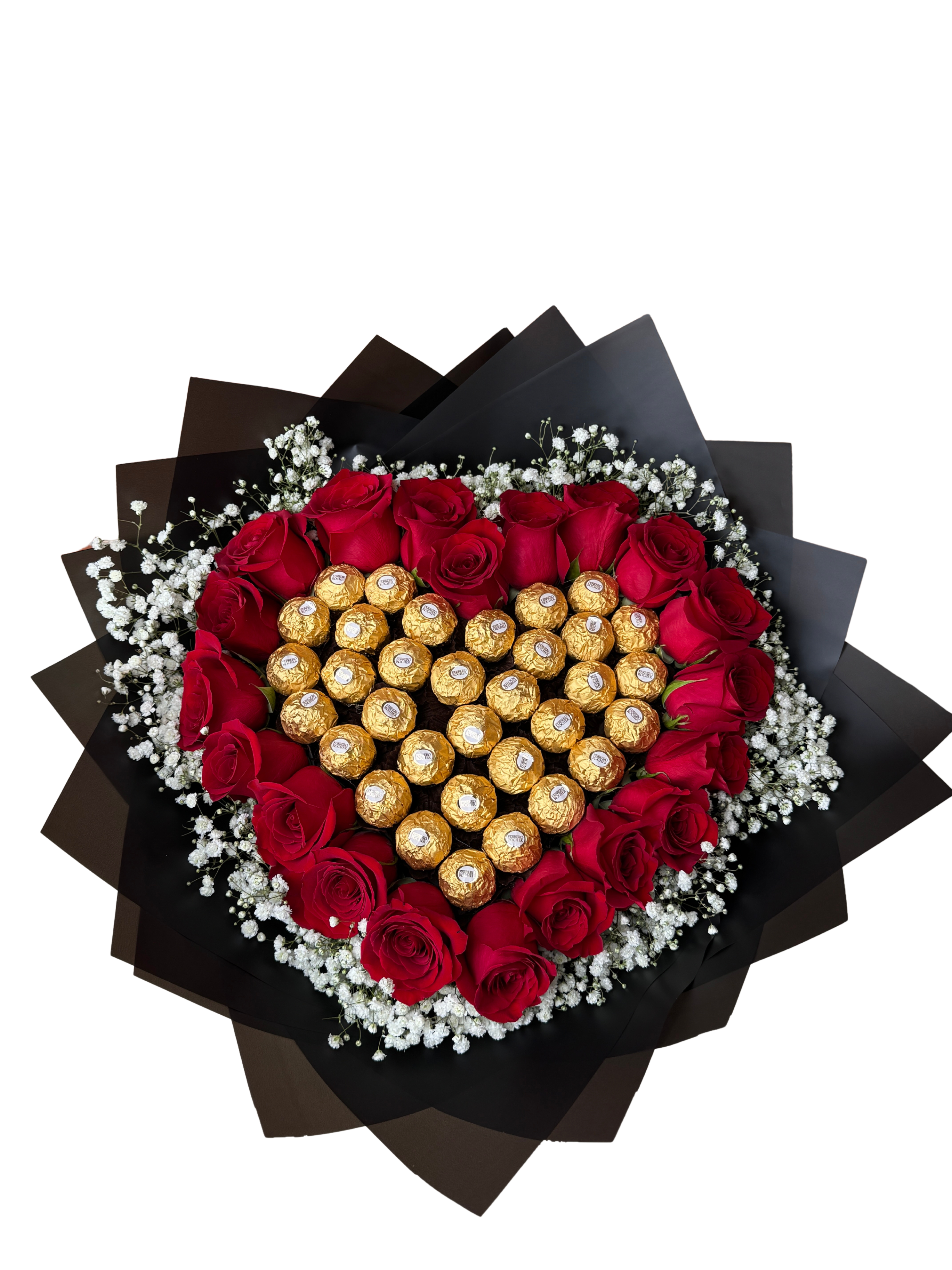 Sweet Love - A heart-shaped arrangement of vivid red roses makes an immediate romantic statement - the perfect anniversary bouquet or Valentine's Day gift that tells the person you're thinking of "you are my favorite." Sweet Love combines classic red roses with a gift-like center of gold-wrapped chocolate truffles, so she'll get both the beauty of fresh blooms and the indulgence of chocolate in one memorable presentation.  Delicate white baby's breath frames the roses, softening the bold red-and-gold palette and creating gentle contrast against the dramatic black wrapping paper that lends a modern, luxe edge. The piece is compact and decorative, designed to sit on a table or bedside with an easy-to-display heart silhouette. Chocolates are nestled in the center for a flourish of texture and shine alongside the soft petals.  Ideal for celebrating romantic milestones - anniversaries, Valentine's Day, or simply to make someone feel truly seen - this arrangement reads as both sentimental and celebratory. Order with standard delivery sizing; the compact form makes care simple: keep blooms in a cool spot away from direct sun, refresh water as needed, and enjoy the roses and truffles together for an extra-special surprise.