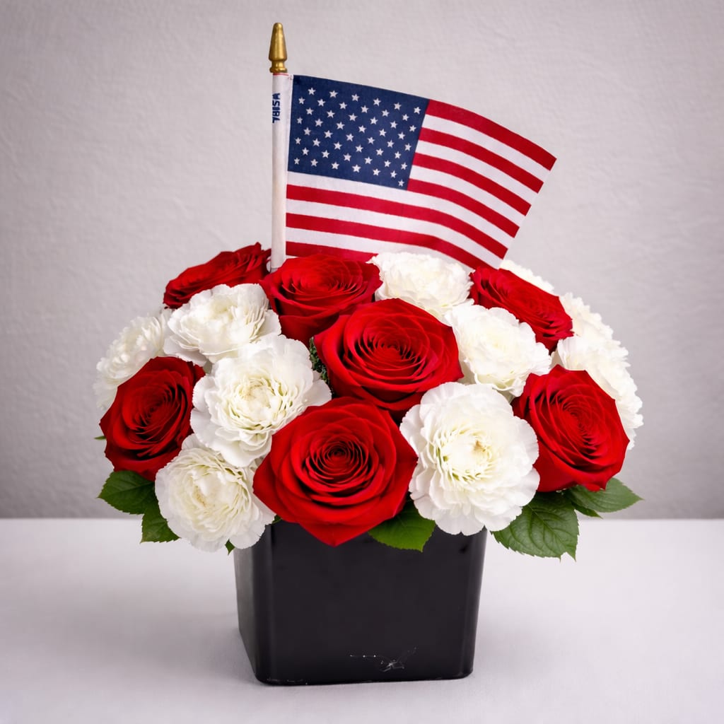 Patriotic Honor Bouquet - A stunning patriotic arrangement featuring fresh red roses and white blooms in a modern blue vase, accented with an American flag. This elegant design represents honor, love, and remembrance. Perfect for Memorial Day or any special occasion.