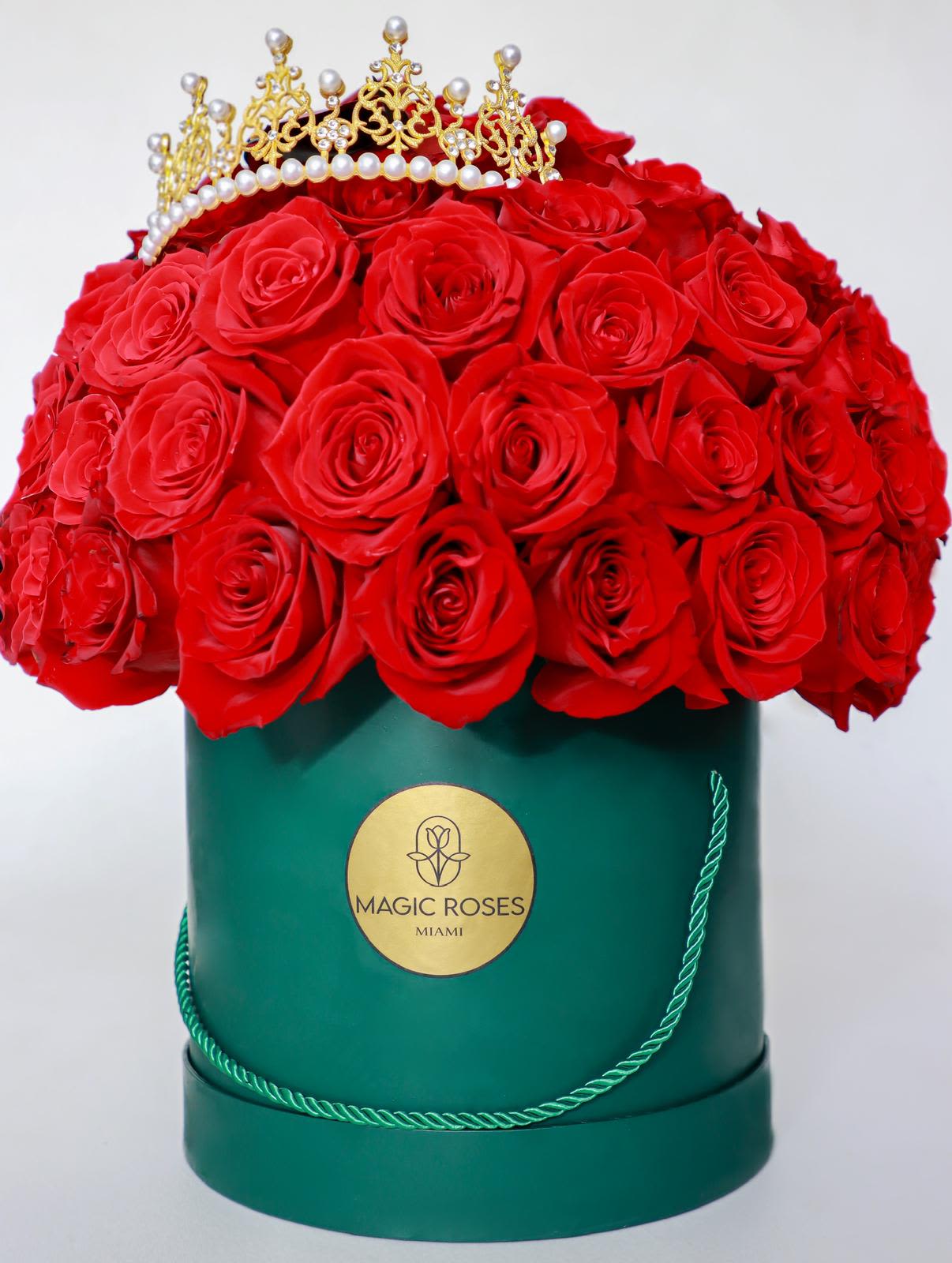 Royal Passion - A dense dome of vivid red roses crowned with a gold-toned decorative crown makes a bold statement-perfect as an anniversary roses arrangement or a luxurious  gift that reads romantic and celebratory. The combination of saturated red blooms against the deep green hat box creates an immediate visual impact, while touches of white and yellow in the composition add warmth and brightness that keep the design from feeling one-note.  This floral arrangement is presented in a round green hat box trimmed and finished with a rope handle and brand label for an elevated presentation. Roses are packed tightly to form a plush, uniform dome; the compact, structured size makes it ideal for display on a dresser, entry table, or office desk without overwhelming the space.  Give this to the person you're celebrating when you want them to feel adored and seen-whether marking an anniversary, birthday, or a special romantic moment. The hat box keeps blooms neatly contained; to maintain freshness, keep the arrangement in a cool spot out of direct sunlight and follow any included care instructions when watering or refreshing the floral foam.