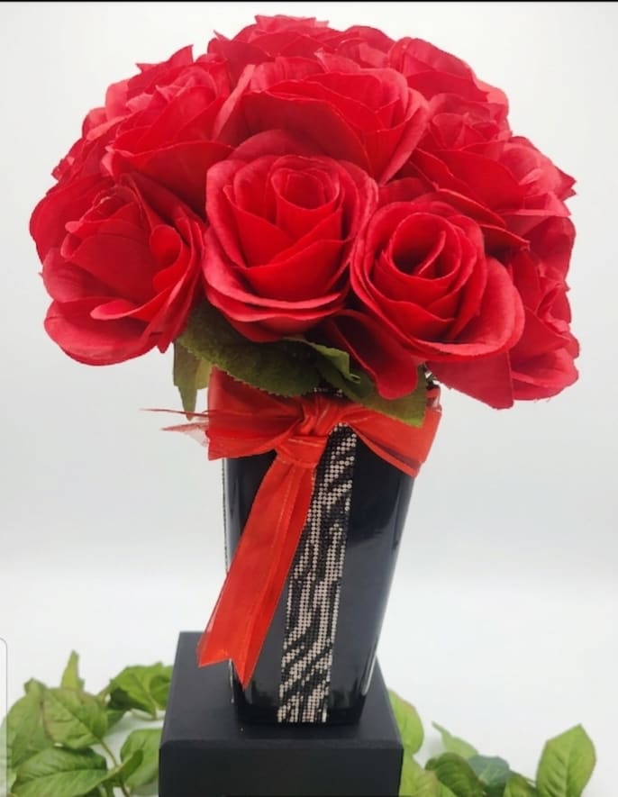The red carpet - ​A striking, high-contrast arrangement designed to command attention. Vibrant, velvety red roses are tightly clustered into a dense, luxurious dome, creating an instant focal point of classic passion. The bouquet is dramatically paired with a sleek, glossy black vase, wrapped in a bold, shimmering zebra-pattern rhinestone ribbon and tied with a coordinated red satin bow. Perfect for a grand gesture, an upscale event, or anyone who loves high-fashion glamour and unapologetic sparkle.