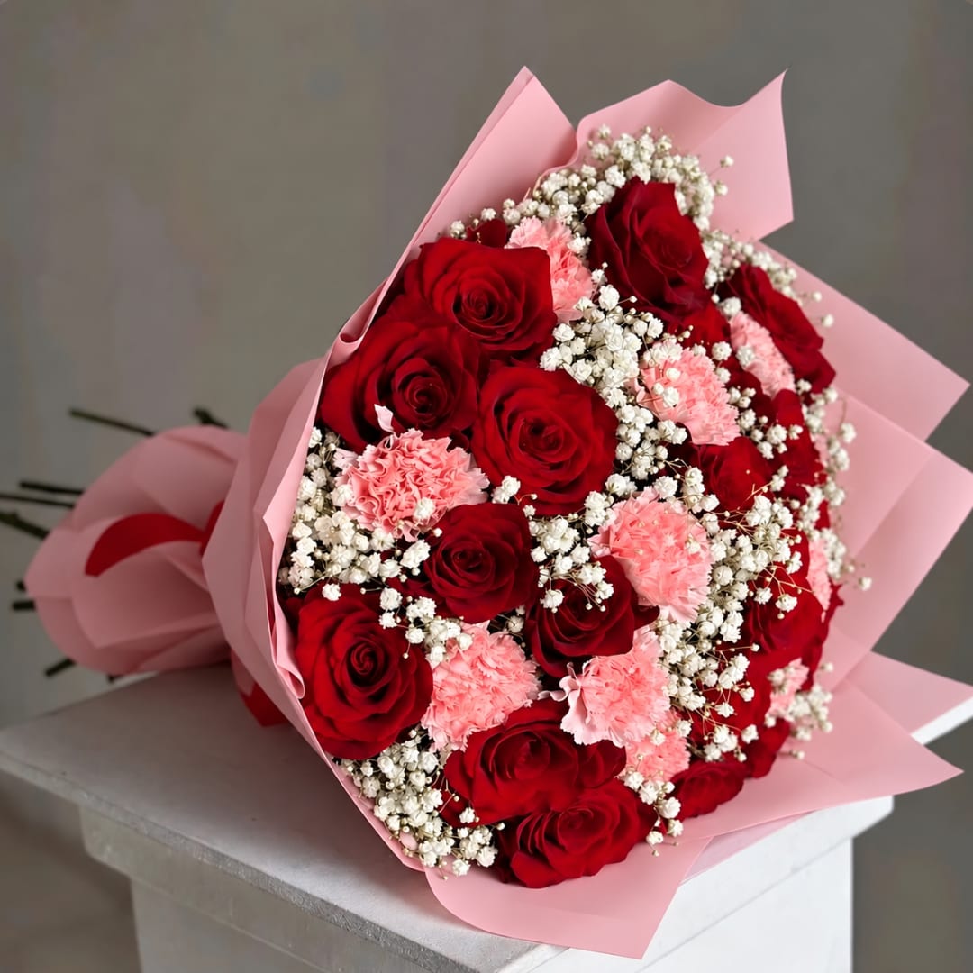 Bouquet of red roses and pink carnations wrapped in pink paper