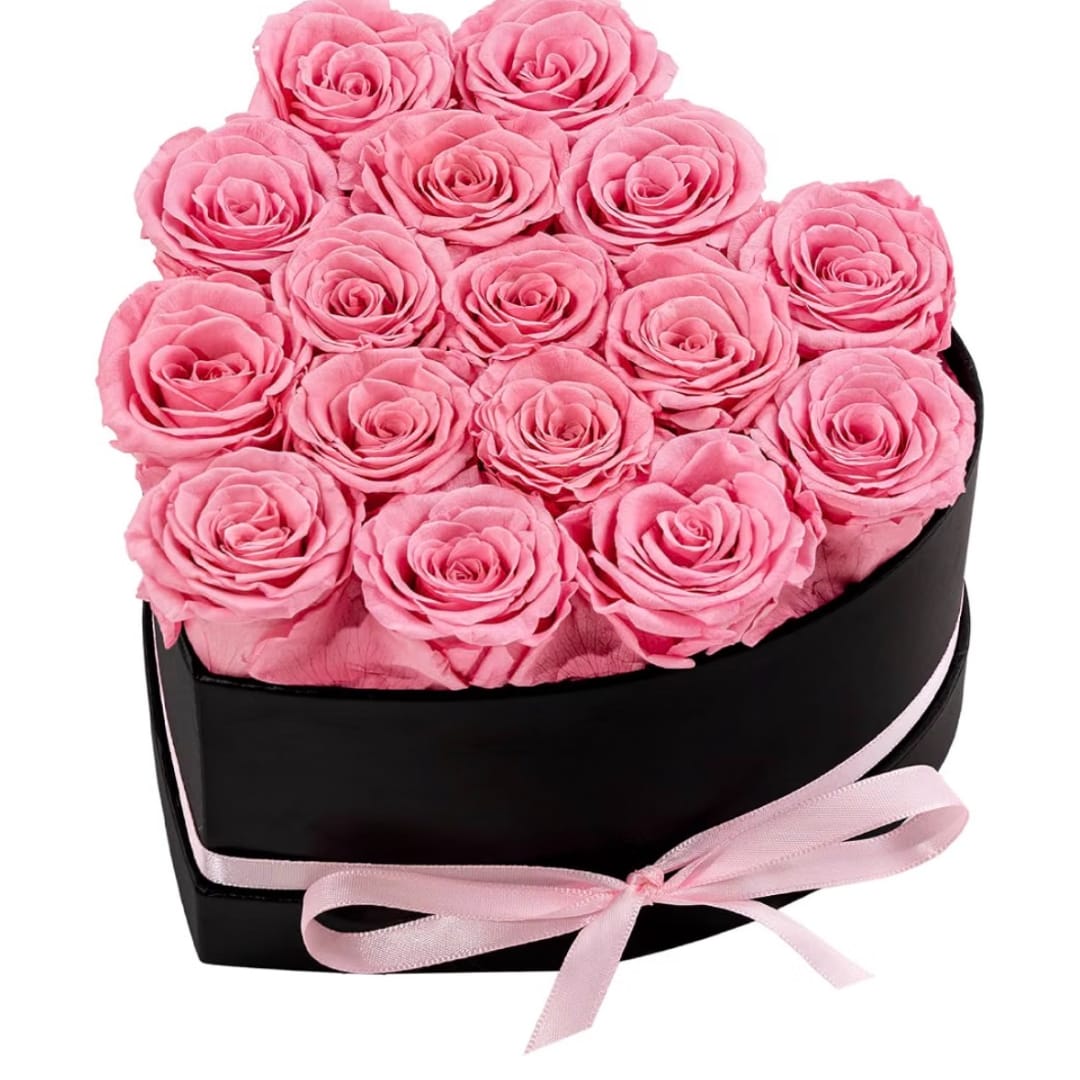 Pink roses arranged in a black heart-shaped box with a pink ribbon