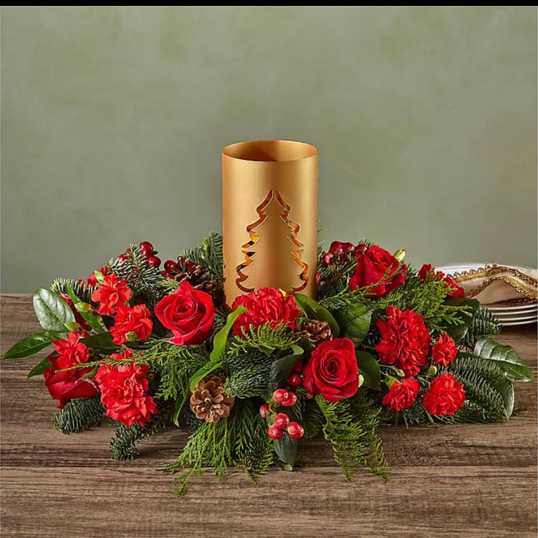 Red roses and carnations arranged around a gold candle holder centerpiece