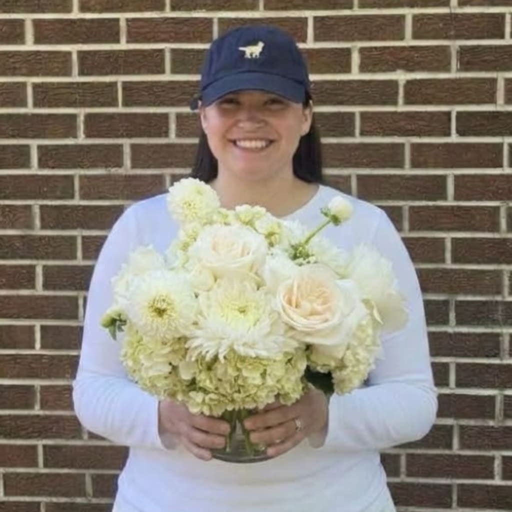 Woman holding a white floral bouquet in a glass vase
