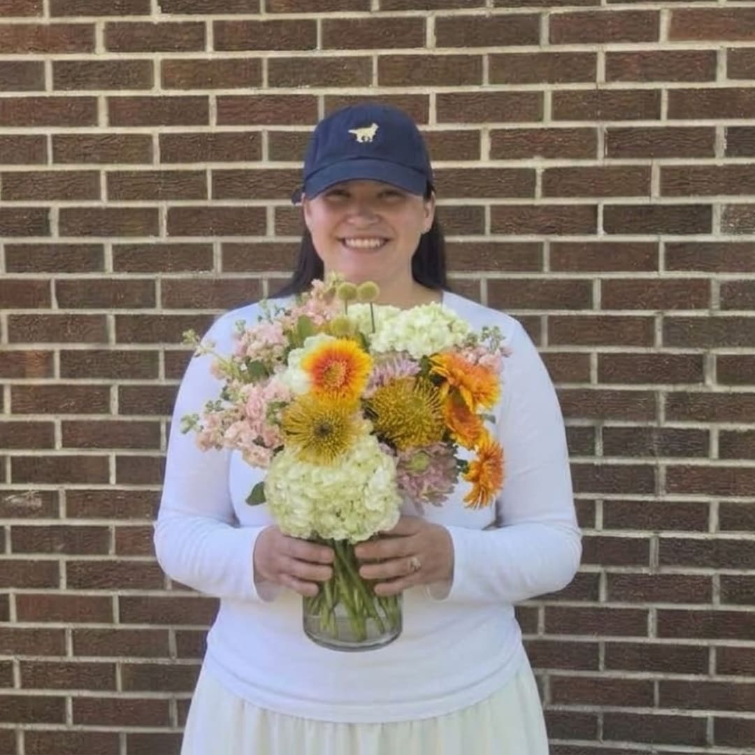 Woman holding a mixed bouquet in a glass vase