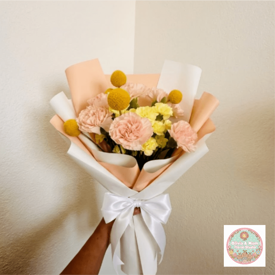Golden Hour - Radiant, warm, and glowing—Golden Hour captures that perfect late-afternoon light. A mix of peach and yellow tones feels like a warm hug, making it a sophisticated tribute for another year well-lived.  This seasonal bouquet features:  Peach Carnations  Yellow Mini Carnations  Yellow Billy Buttons  Garden Greens  Presentation: Expertly wrapped in our signature textured paper and tied with satin ribbon. Prefer a vase? Add one to your cart to complete the look.  Personal Touch: We’ll include a custom card message with every order. You’ll be able to write your message at checkout.  Please Note: All flowers are subject to seasonal availability. If a specific bloom isn’t available, our designers will thoughtfully substitute with flowers in a similar shape, style, and color.  Standard size shown. Vase upgrade is optional.   Floral Care Guide  Your arrangement arrives in our signature "double wrap" and is nestled in a protective box. While the stems are secured with a wet wrap for transit they are ready for a full drink!   Unpack: Gently lift the bouquet from the box. Remove the plastic bag and wet towel from the stems. Trim &amp; Hydrate: Trim 1/2" off stems at an angle and place in a clean vase with cool water. Refreshed: Change water daily for a long-lasting bloom.  