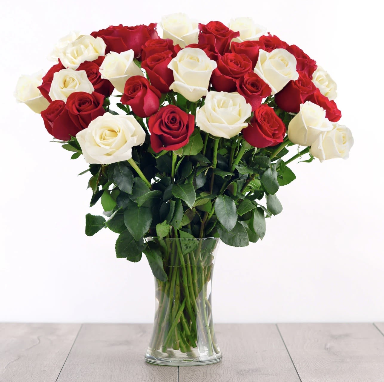 Eternal Harmony Bouquet - Celebrate timeless beauty and balance with our Eternal Harmony Bouquet, a stunning arrangement of classic red and ivory roses. Each bloom is carefully selected to symbolize love, purity, and unity — perfect for romantic gestures, anniversaries, or simply brightening a special space. Arranged in a clear glass vase, this bouquet radiates grace and sophistication, making it a beautiful centerpiece or heartfelt gift.  12 or 24 Beautiful Roses ready to surprise your loved one on your best day.