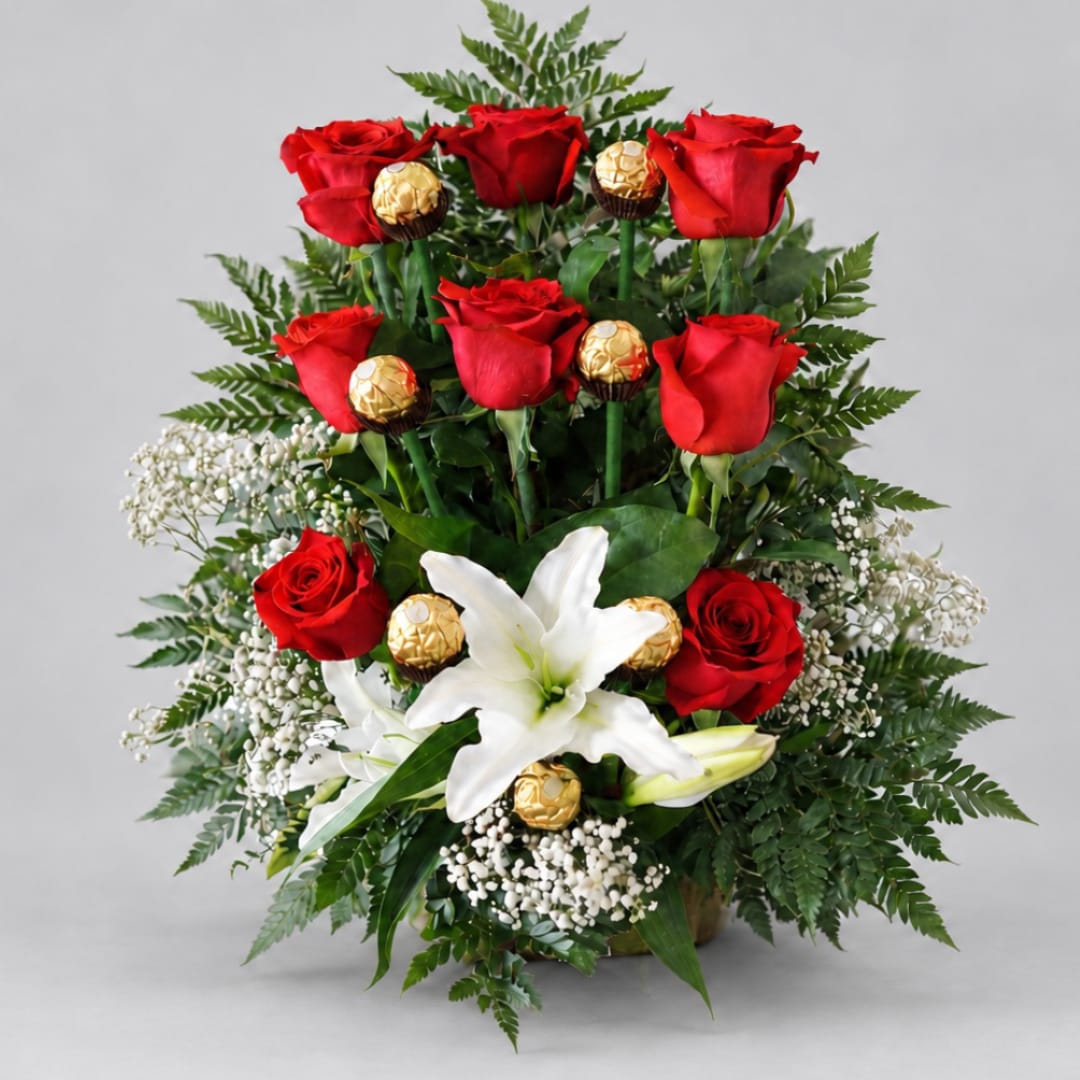 Red roses and white lilies arranged with gold-wrapped chocolates in a vase