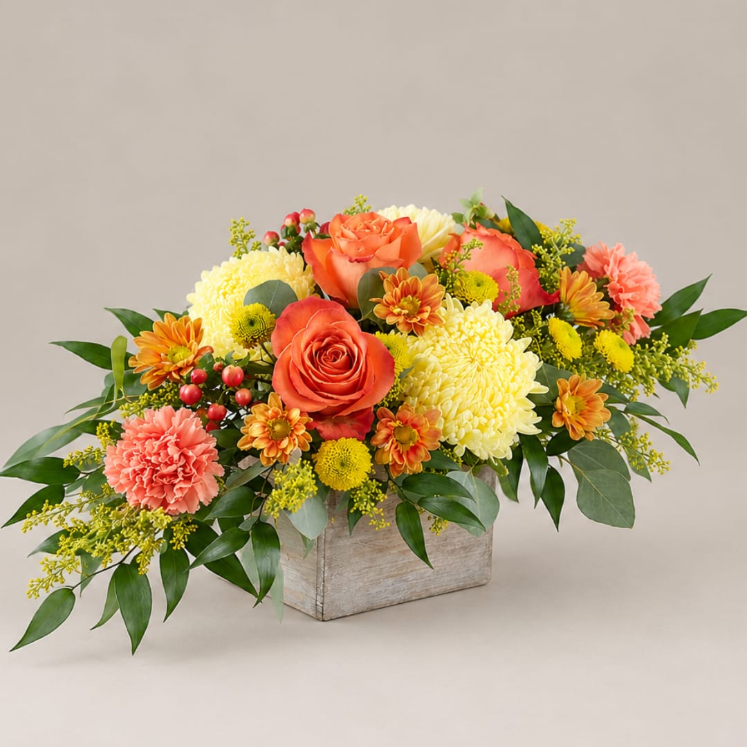 Orange roses and yellow mums arranged in a low wooden box