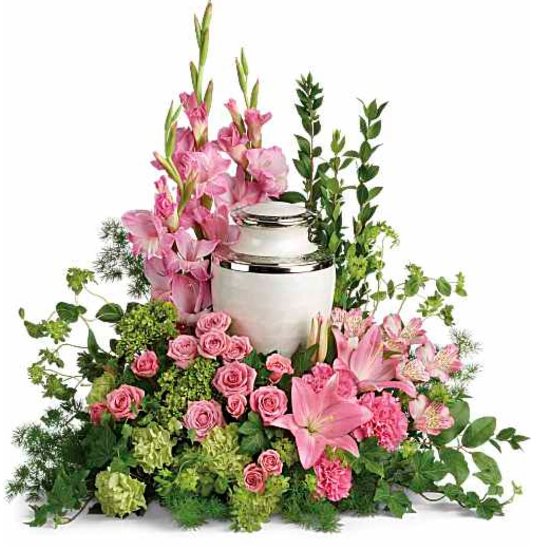 Pink lilies and roses arranged around a white urn with greenery