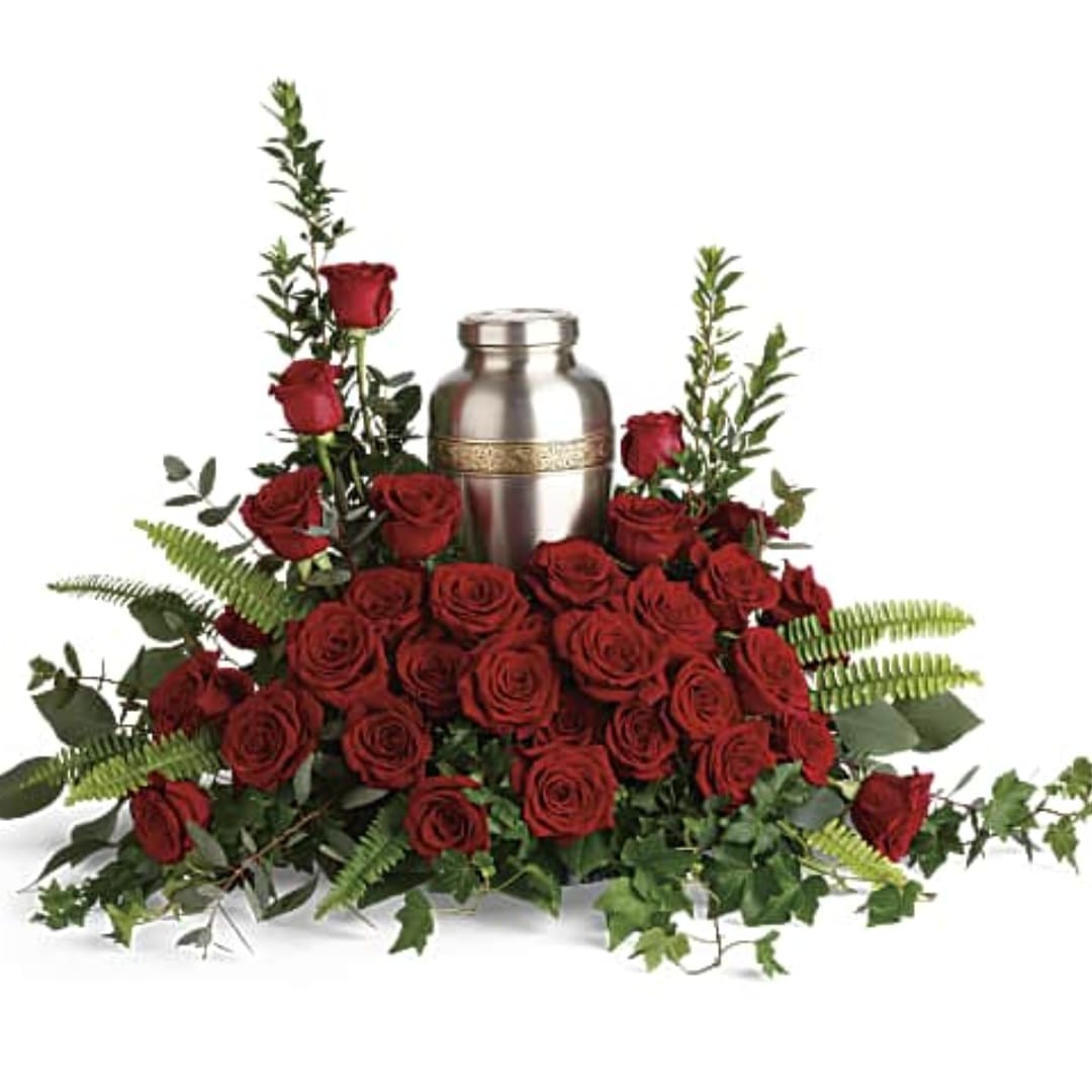 Red roses arranged around a silver urn with greenery