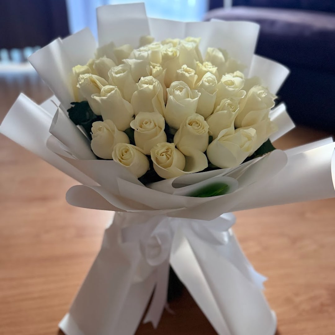 Bouquet of white roses wrapped in white paper with a ribbon
