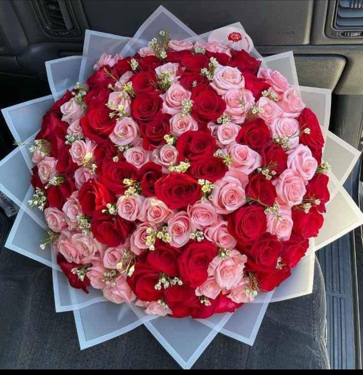 BUCHONES - A lush, hand-tied floral bouquet built around classic roses and lilies-BUCHONES is a romantic bouquet perfect for anniversaries, Valentine's Day, or any occasion when you want the person you're thinking of to feel truly cherished. The rounded dome shape and tightly packed blooms create an immediate visual impression of abundance; deep red and blush pink set a passionate tone while white and purple accents soften the look into something tender and celebratory.  This arrangement combines red, pink and white roses with pink lilies, snapdragons, pale green lily buds and small white filler blooms for texture and depth. Finished in layered paper wrap-white and pale pink sheets with a tidy paper sleeve-the bouquet reads polished and gift-ready straight from the florist. The dense, rounded composition is substantial in size and designed to present beautifully from every angle.  Give this to the one you love to mark a milestone, say "I'm thinking of you," or make a birthday feel elevated-she'll arrive at the moment feeling seen and celebrated. Care is simple: keep stems trimmed and fresh water in the vase; if you'd like help selecting size or delivery timing, choose your preferred option at checkout.