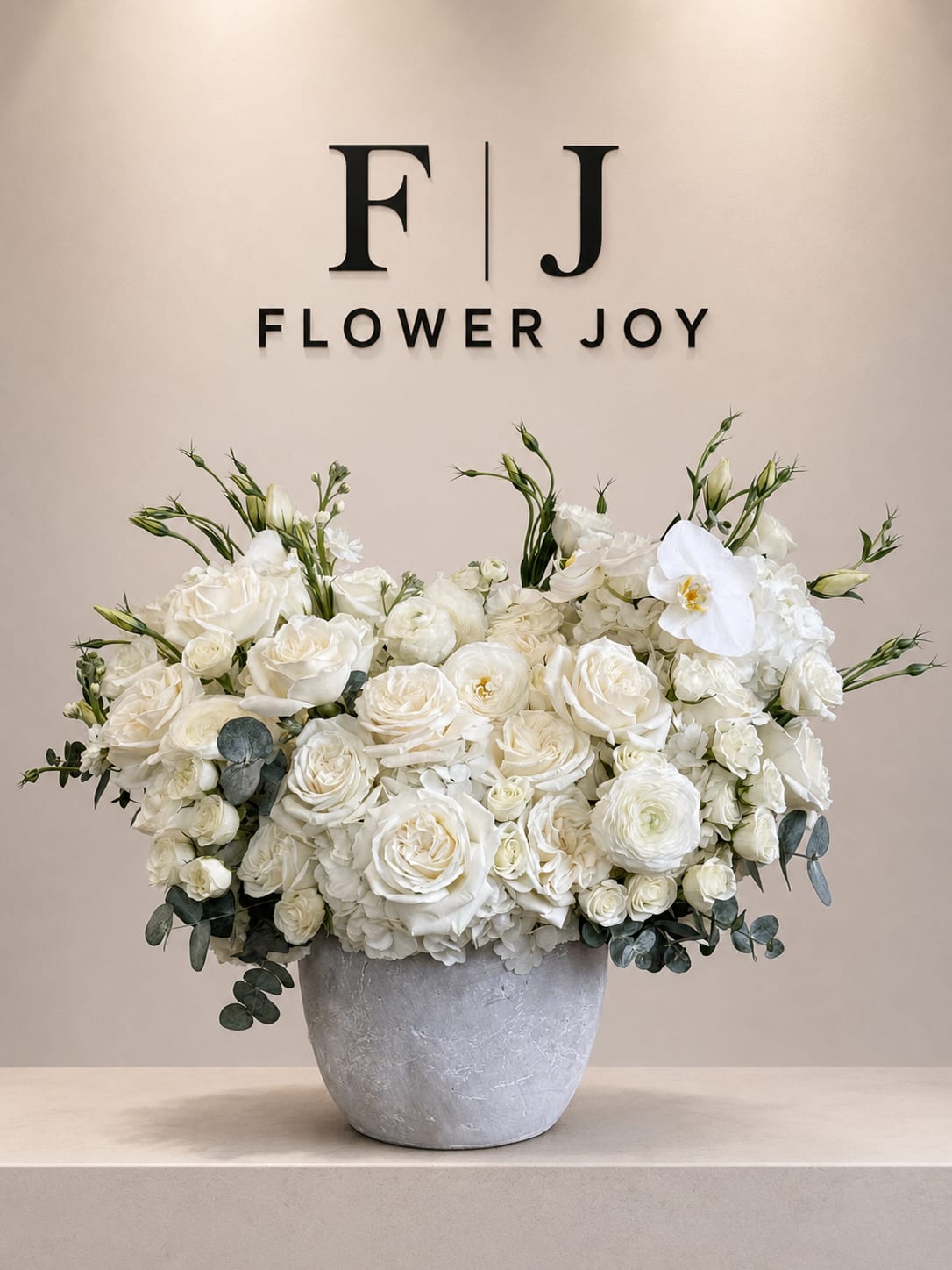 White rose arrangement in a gray vase with eucalyptus accents