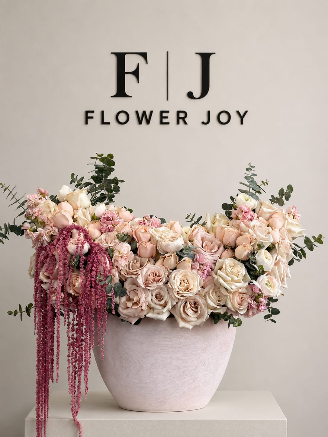 Large blush and cream rose arrangement in a pale vase