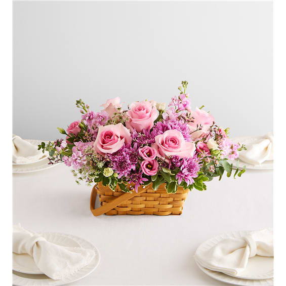 Pink roses and purple flowers arranged in a wicker basket
