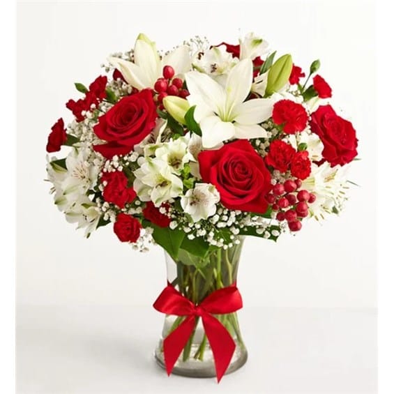 Bouquet of red roses and white lilies in a clear glass vase with a red ribbon