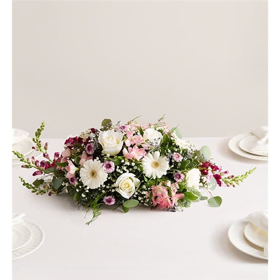 Low floral centerpiece with white and pink blooms on a table
