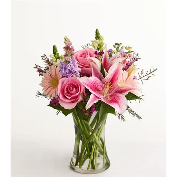 Pink roses, lilies, and daisies arranged in a clear glass vase