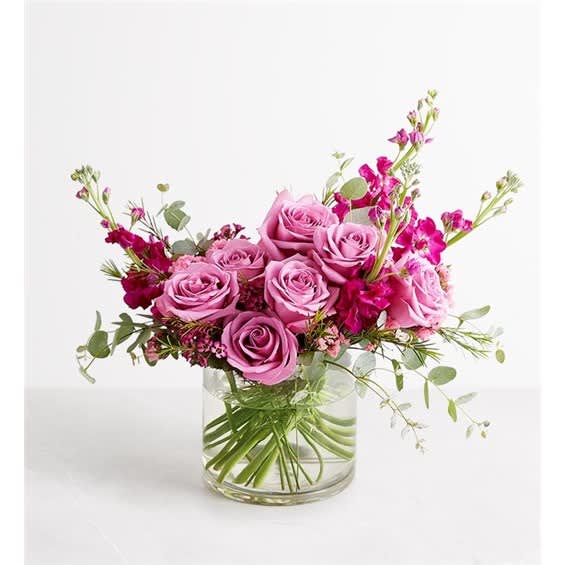 Pink rose bouquet in a clear glass vase with airy magenta accents