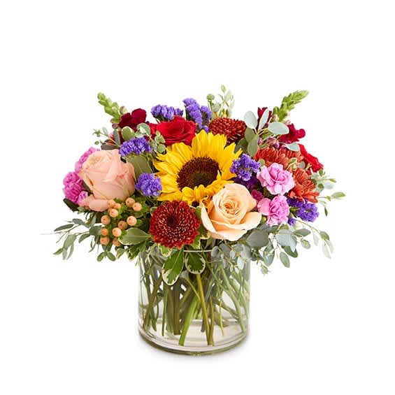 Mixed bouquet of sunflowers, roses, and colorful blooms in a glass vase