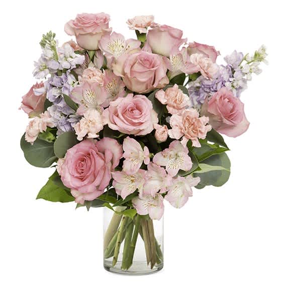 Pink roses and pastel flowers arranged in a clear glass vase