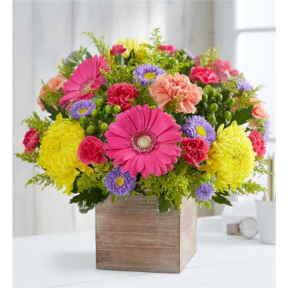Colorful mixed bouquet in a wooden box with pink, yellow, and purple flowers
