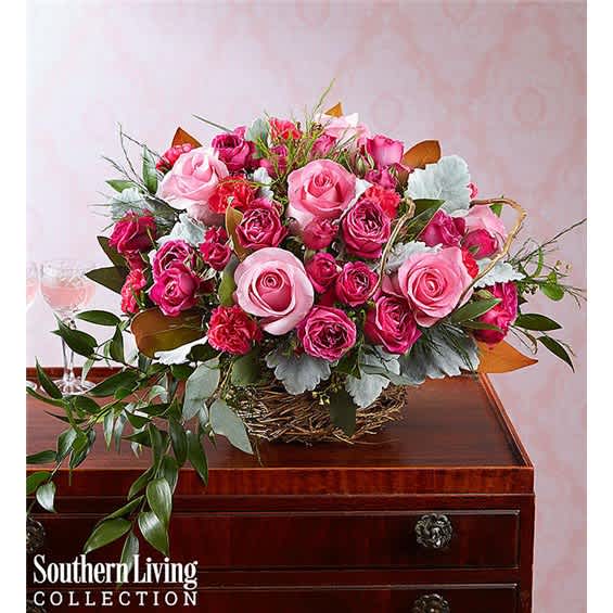 Pink rose bouquet in a low woven basket with trailing greenery