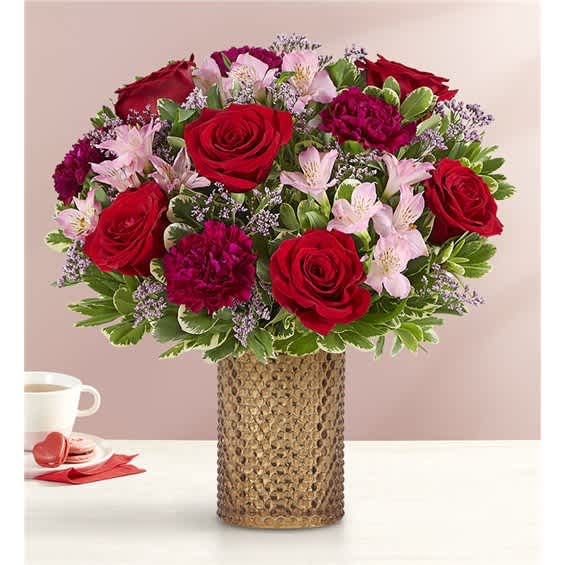 Red roses and pink flowers arranged in a textured vase