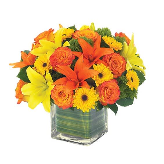 Orange and yellow flowers arranged in a clear square glass vase