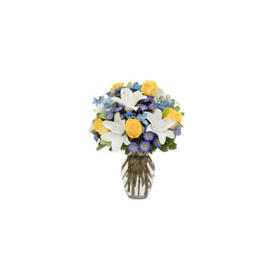 Bouquet of white lilies, yellow roses, and blue flowers in a glass vase