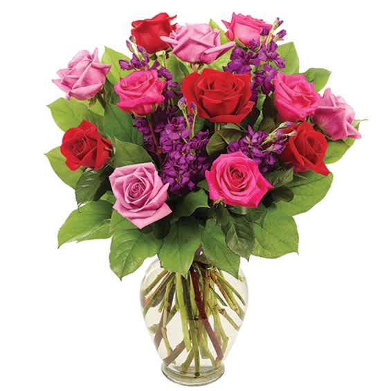 Bouquet of red, pink, and purple roses in a clear glass vase