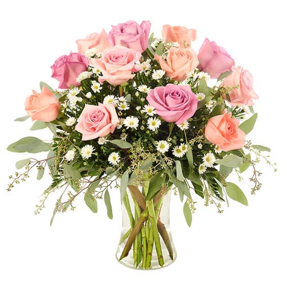 Pink and peach roses arranged in a clear glass vase with small white daisies.