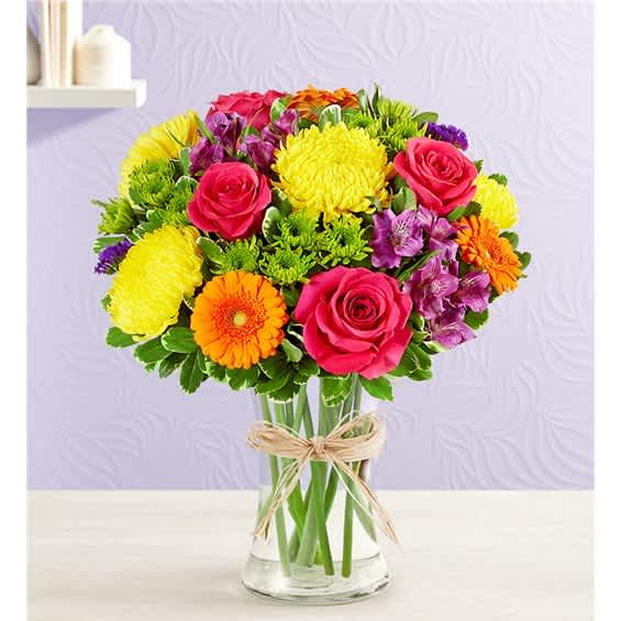 Colorful mixed bouquet of roses, chrysanthemums, and gerbera daisies in a glass vase
