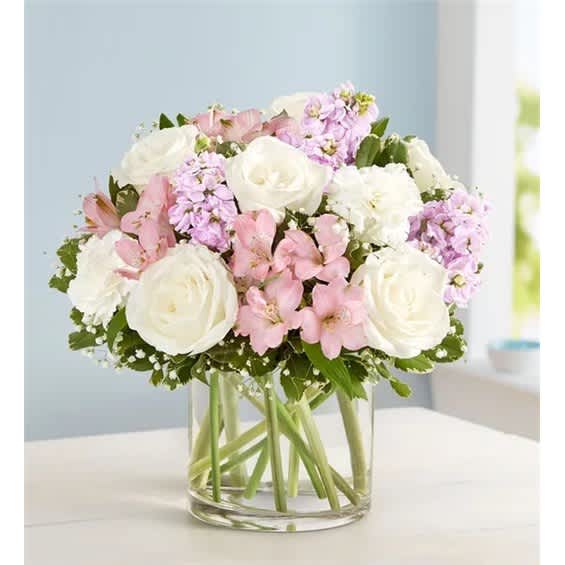 Bouquet of white roses, pink flowers, and lavender blooms in a clear glass vase