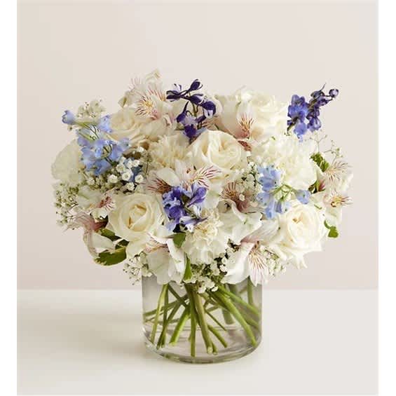 White and blue mixed bouquet in a clear glass vase