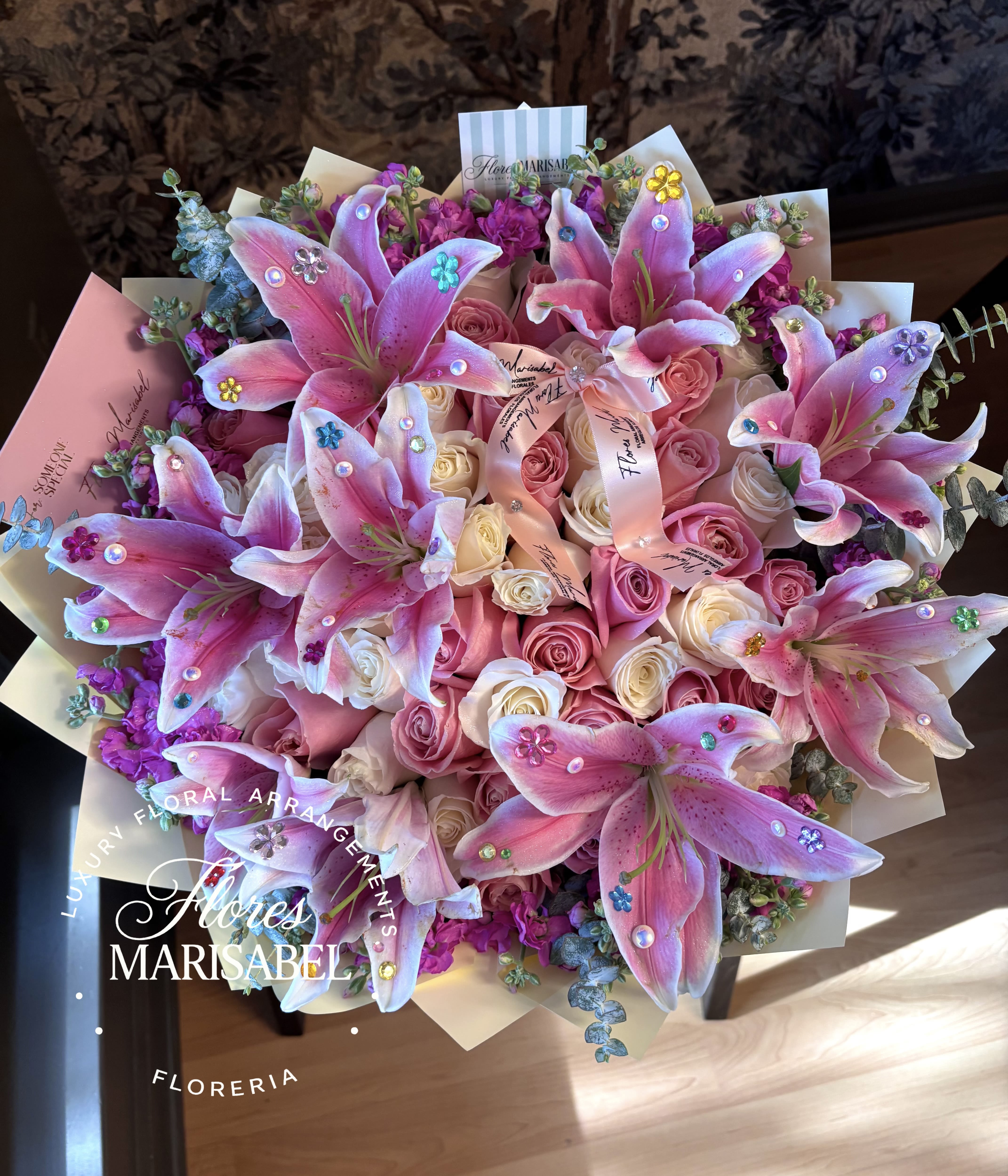 Fancy Nancy  - 50 roses pink and white, flower rim (flowers may vary), lilies with rhinestones. (For natural lilies minimum of 5 days needed. Otherwise artificial lilies will be used)  *card not included 