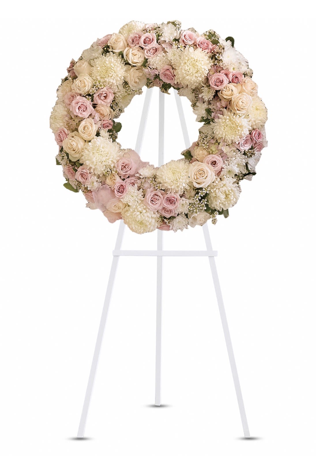Peace Eternal Wresth - Soft blush roses, creamy chrysanthemums, and delicate spray roses form a serene, circular tribute that soothes the eye and the heart - a sympathy wreath designed to honor a life with quiet elegance. As a funeral or memorial arrangement, this flower arrangement communicates gentle remembrance and comfort to the person you're thinking of, giving loved ones a tasteful focal point for service or graveside display.  Packed densely on a white easel stand, the wreath features pale peach, white, and pink blooms arranged in a layered, textured ring. The mix of full rose heads and rounded chrysanthemum blooms creates a lush, romantic surface and a soft palette that reads well from a distance. Sized as a large circular wreath, it arrives ready to stand; no assembly required.