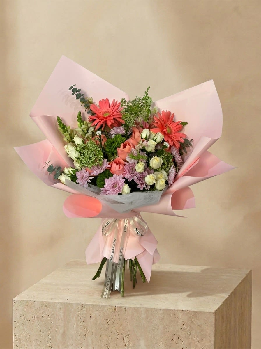 Goldie - A charming bouquet of coral gerberas, roses, and lavender blooms, beautifully wrapped in soft pink. 