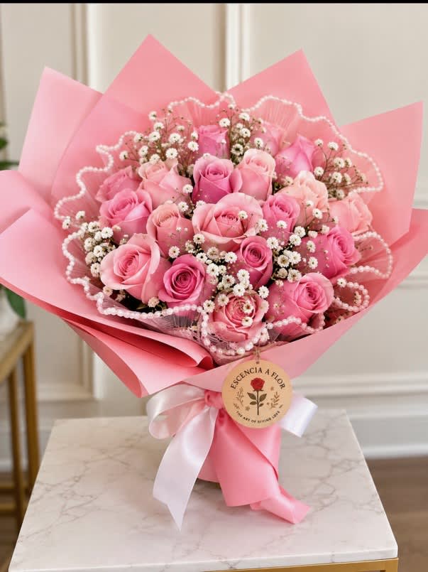 Pink rose bouquet wrapped in pink paper with a white ribbon