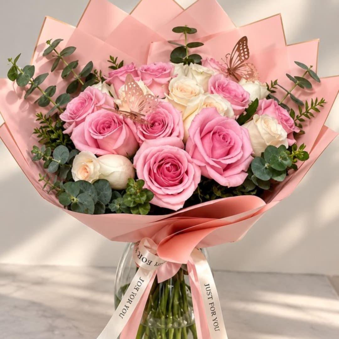 Pink and white rose bouquet wrapped in pink paper with a ribbon