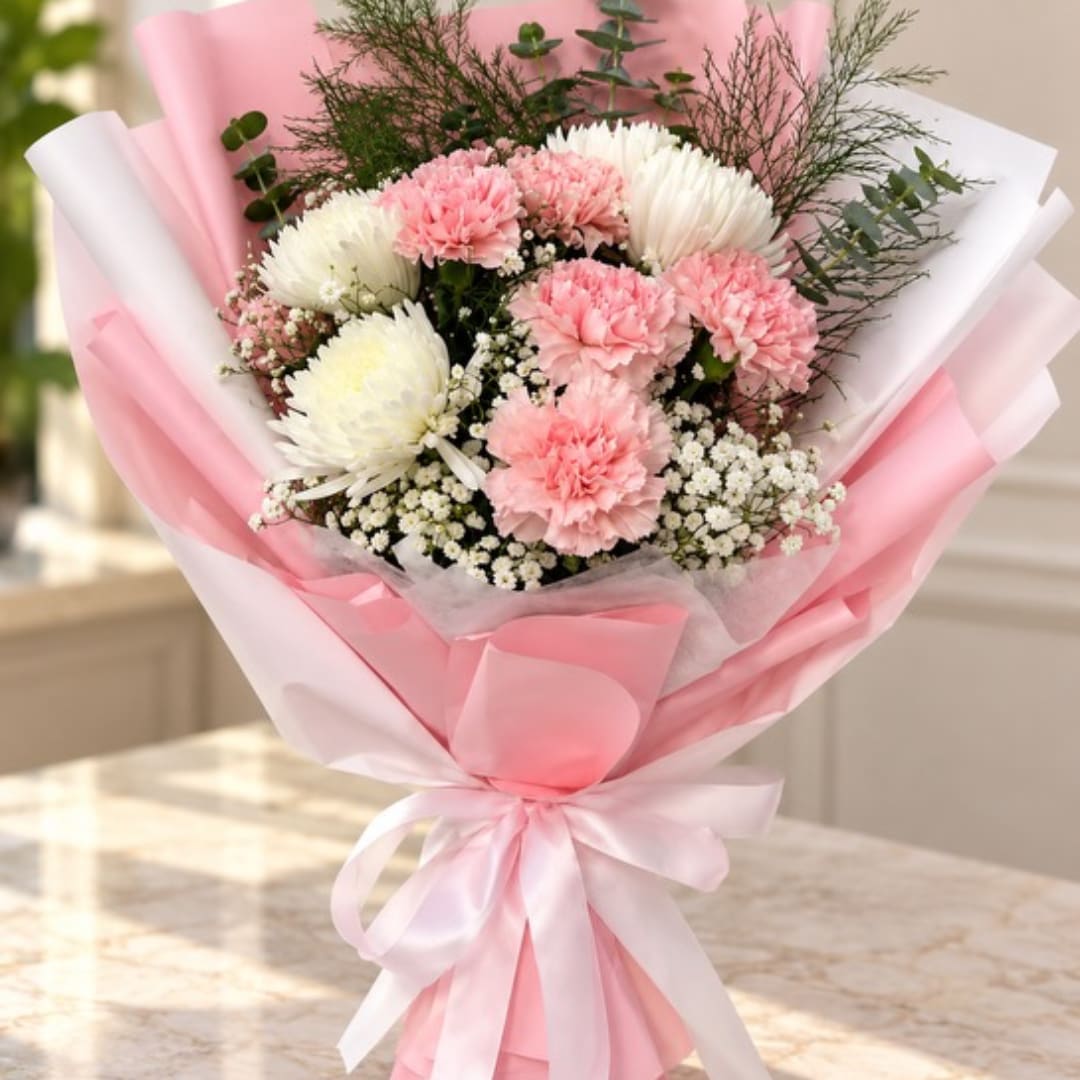 Pink and white bouquet of carnations and small white filler flowers wrapped in pink paper