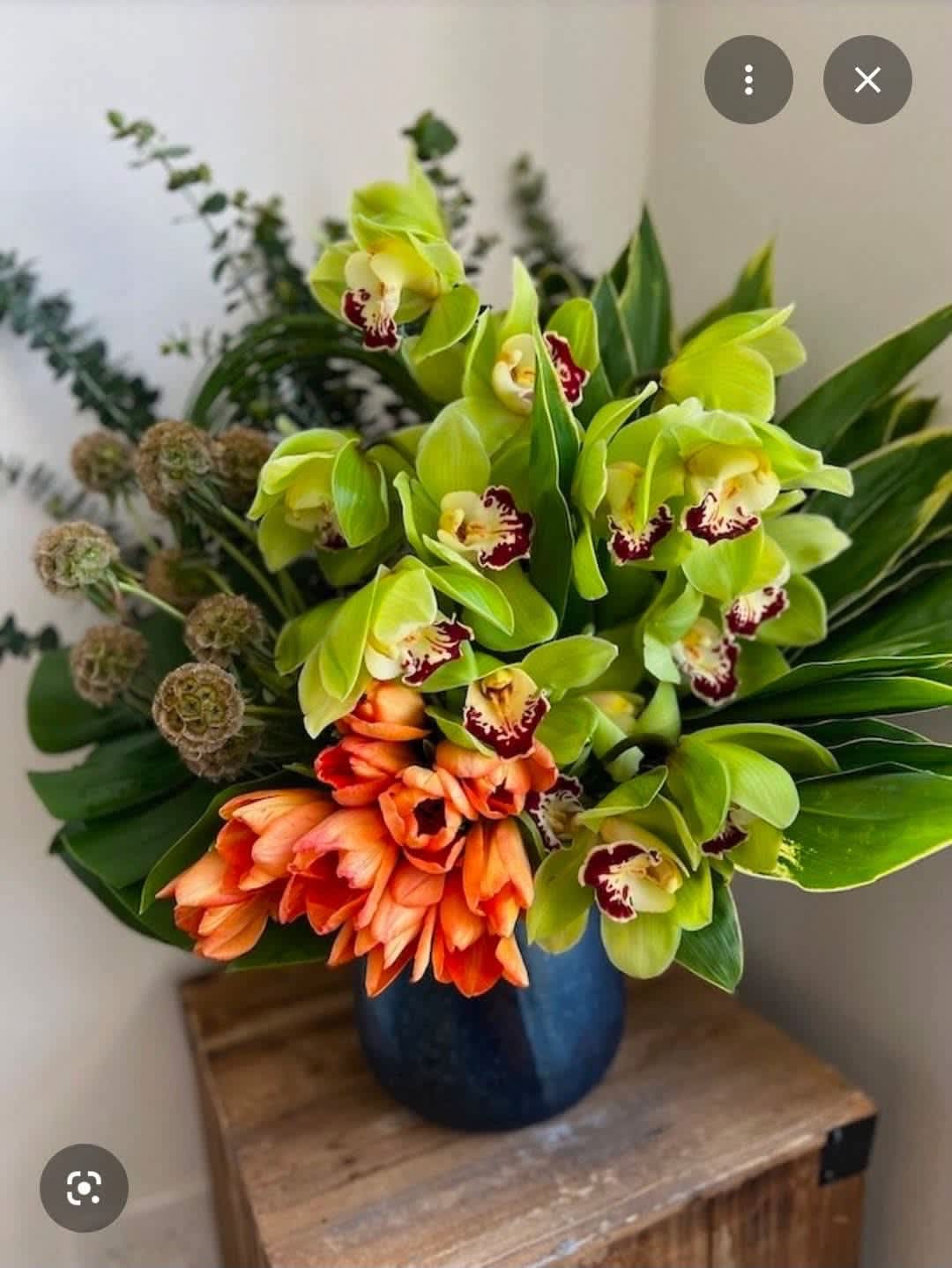 Bouquet of green and orange orchids in a blue vase