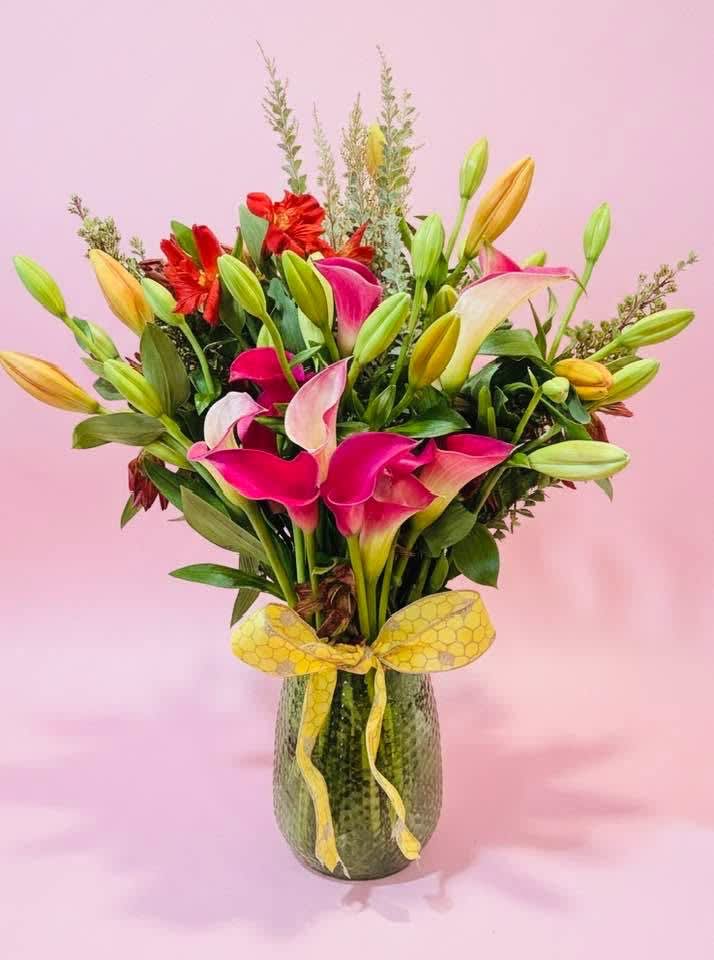 Bouquet of pink and white calla lilies with red flowers in a glass vase